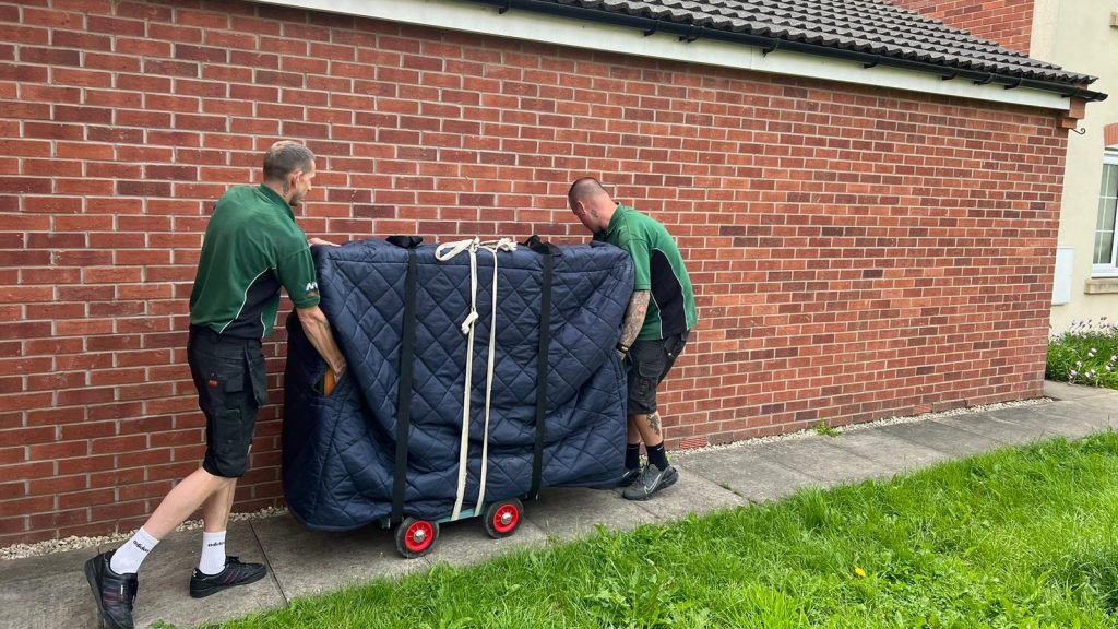 professional movers moving a piano during a house removal in nottingham